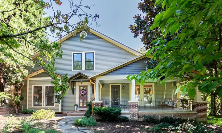 Photo of a craftsman bungalow with a deep front porch, half hidden by trees
